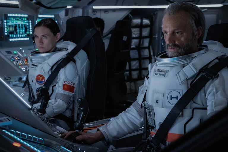 A male and female astronaut sat at a control panel
