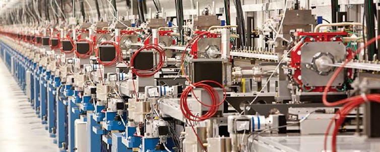 A line of silver pipes and machinery, in a bright room, with red and blue handles.