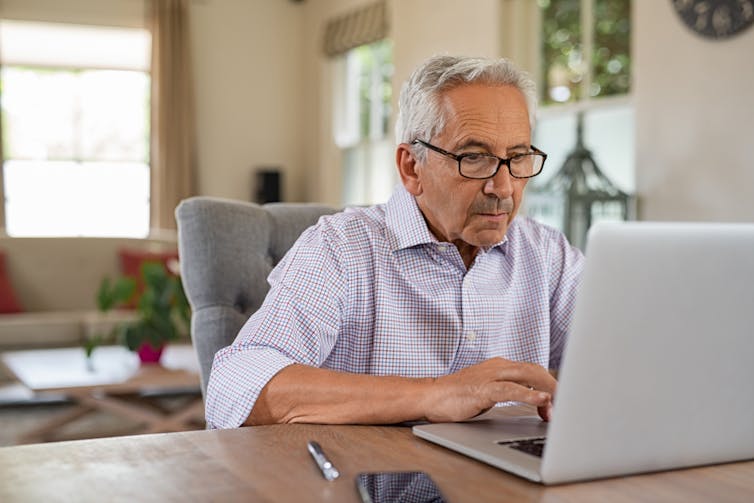 On the laptop, on the desk, the old man at home