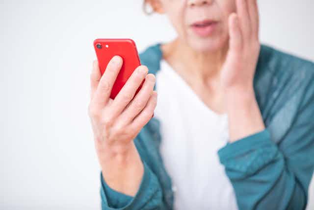 Older woman looking worried looking at smartphone
