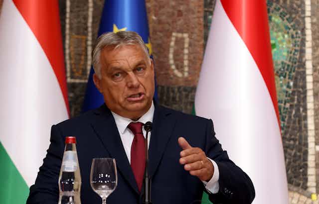 Hungary's prime minister Viktor Orbán gestrures as he makes a speech. In front of him are a bottle and glass containing water.