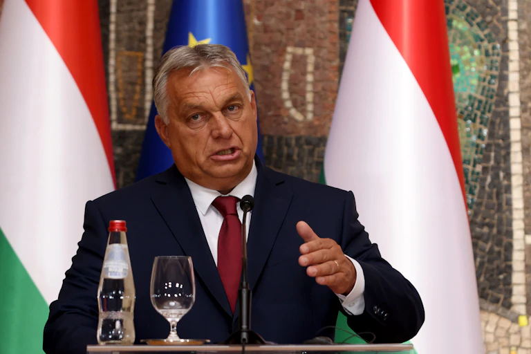 Hungary's prime minister Viktor Orbán gestrures as he makes a speech. In front of him are a bottle and glass containing water.