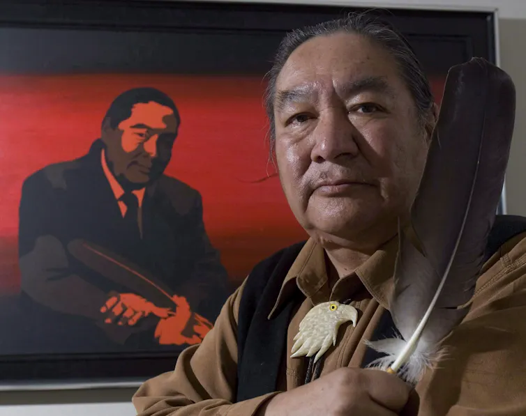 A man holds up two feathers.