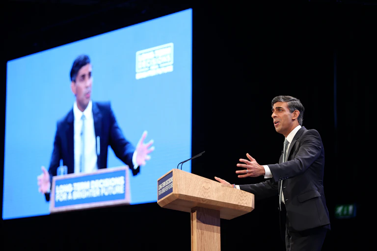 Rishi Sunak giving a speech in front of a big screen