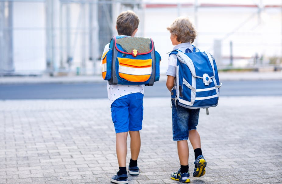 Deux enfants avec des sacs à dos sur le chemin de l'école