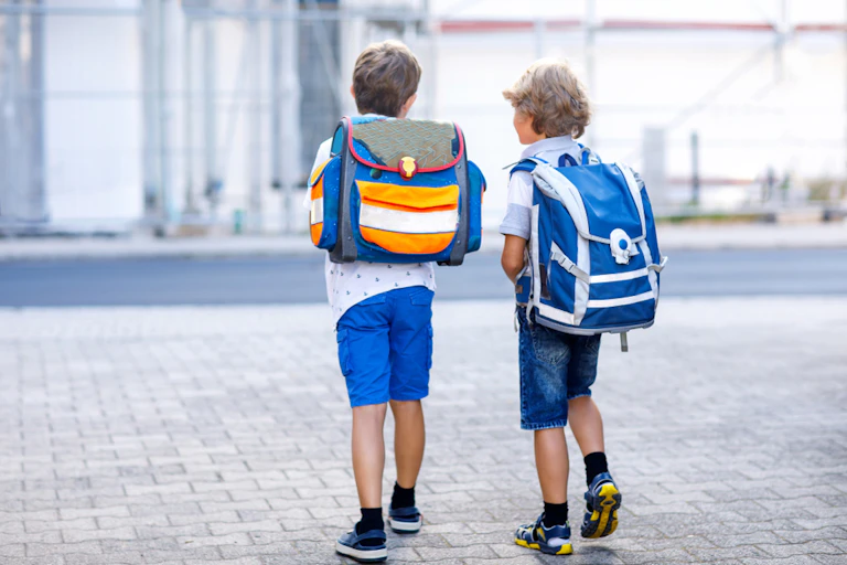 Deux enfants avec des sacs à dos sur le chemin de l'école