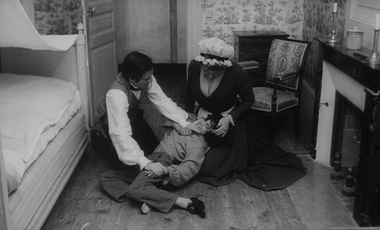 Un hombre y una mujer sentados en el suelo juegan con un niño pequeño.