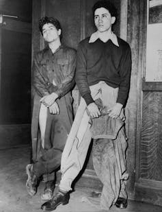 Two men show where their clothes had been sashed by angry white servicemen.
