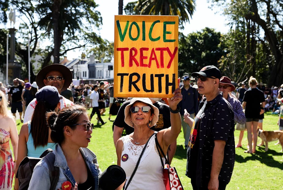 A woman holds up a sign saying Voice Treat Truth.
