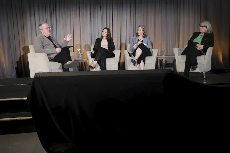 one man and three women seated on a stage in conversation