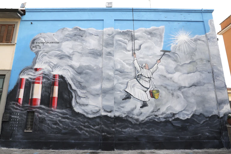 A large graffiti painting shows a man in white robes appearing to clean smog as though he is cleaning windows.