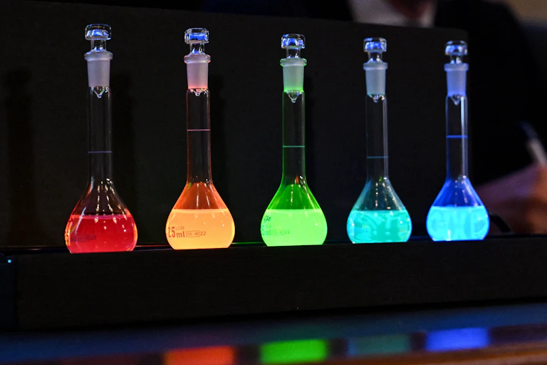 five glowing glass flasks on a darkened table