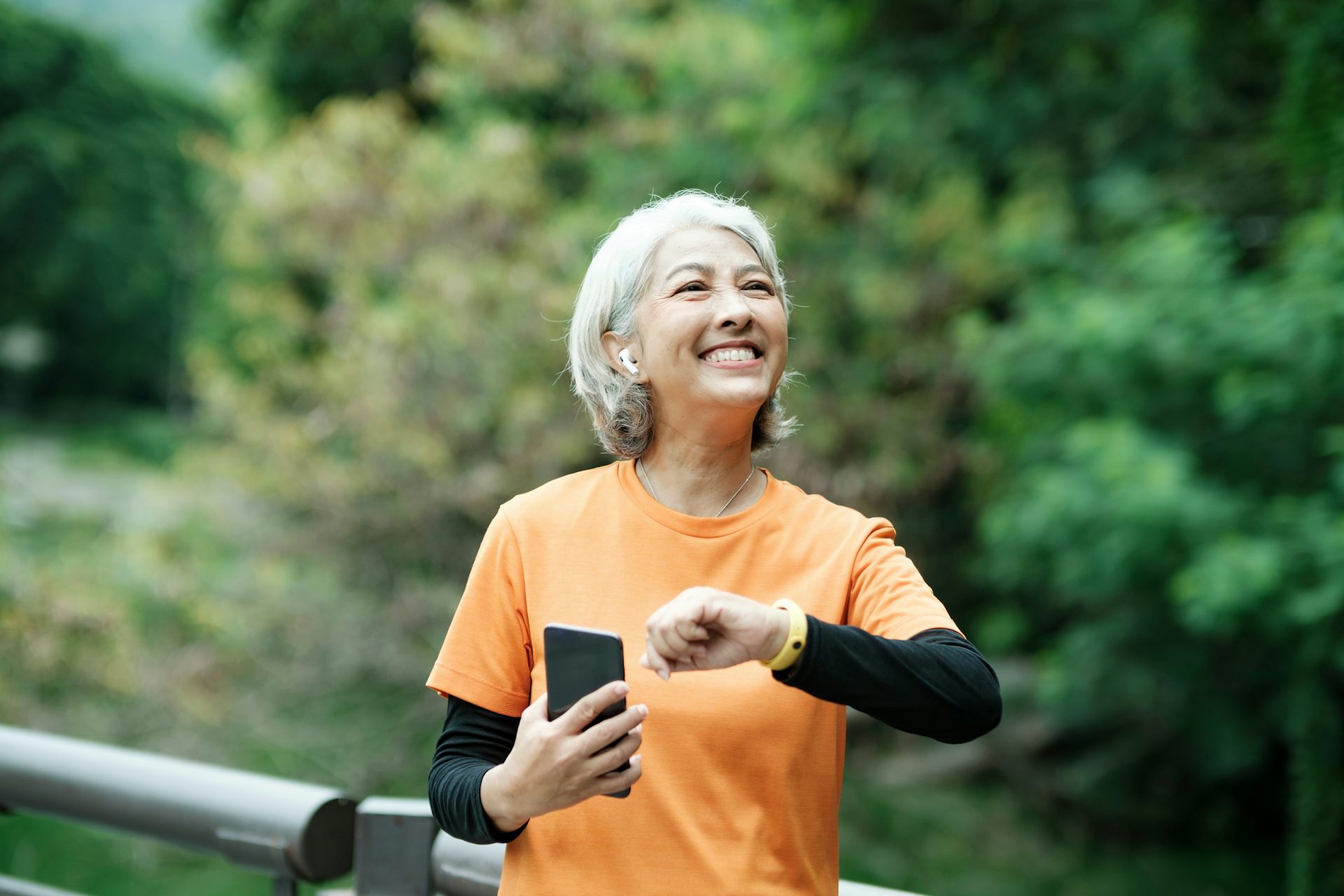 Femme aux cheveux gris en tenue de sport qui consulte son téléphone.