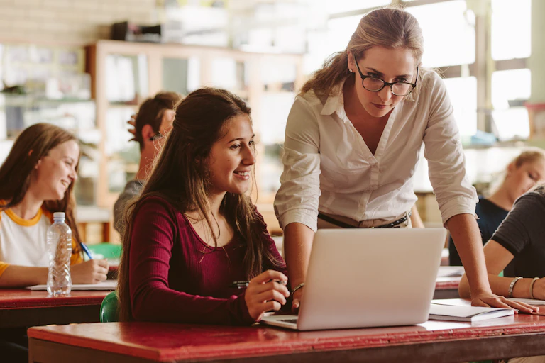 Teacher helping student at laptop