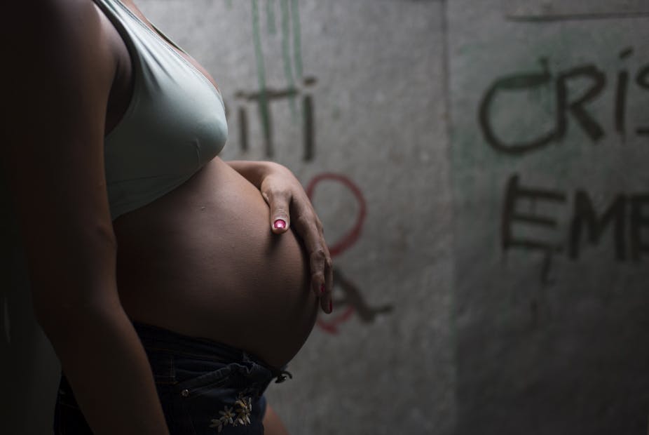 Pregnant woman, in profile, in front of a graffiti wall