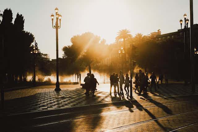 Silhouetted people at golden hour walking down a Paris street