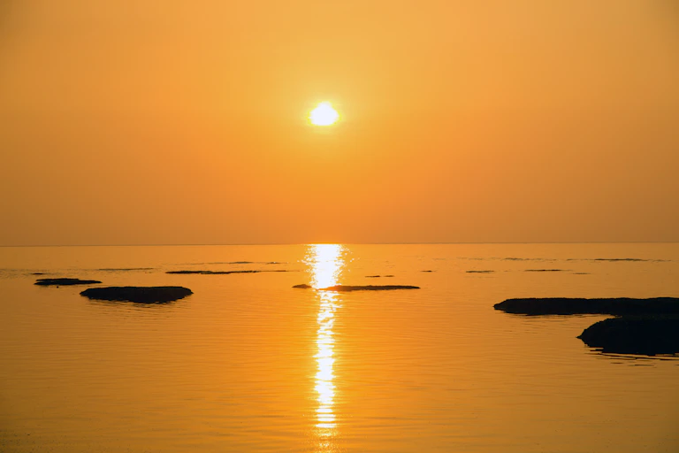 The sun glows on the horizon of the ocean