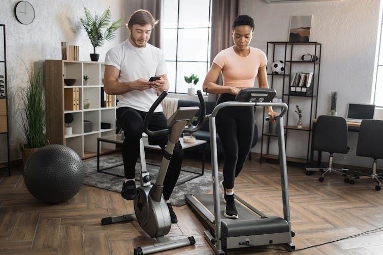 A man on a stationary bike and a woman on a treadmill at home.