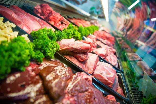 Red meat arranged behind a glass case at a deli counter.