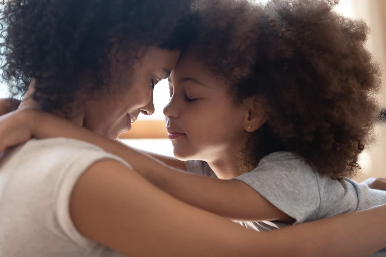 Close up of mother hugging young daughter, foreheads touching