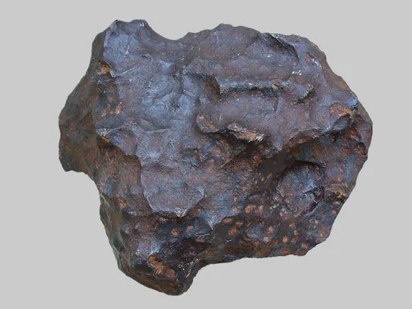 Un meteorito de color marrón grisáceo que es aproximadamente circular con crestas texturizadas.