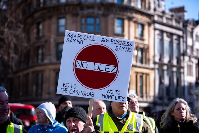 Manifestantes segurando um cartaz em um protesto ULEZ em Trafalgar Square, Londres.
