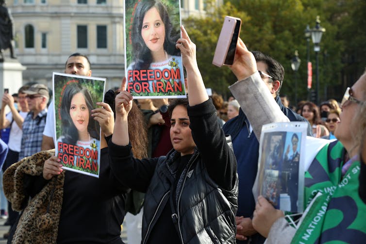 Several Iranian protesters hold photographs of a young woman during a demonstration.