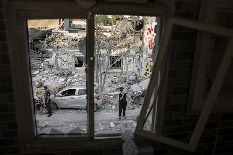 Two people looking at the rubble of a bombed out building.