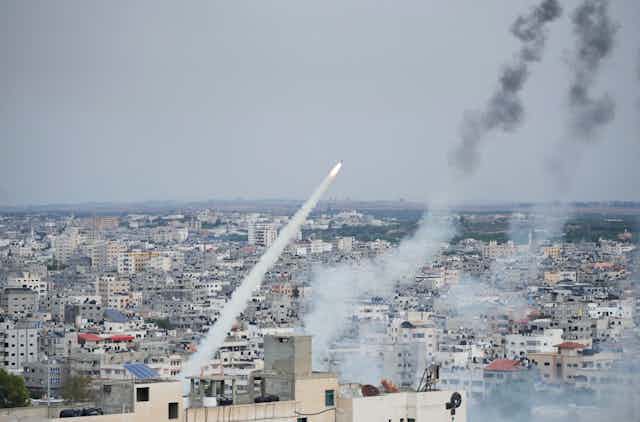 Um foguete com um rastro de fumaça sobrevoa edifícios