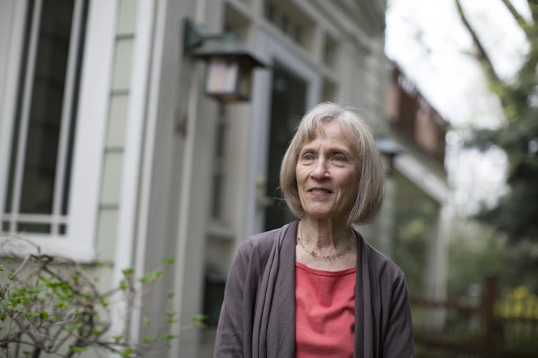 Picture of Claudia Goldin standing outside a house.