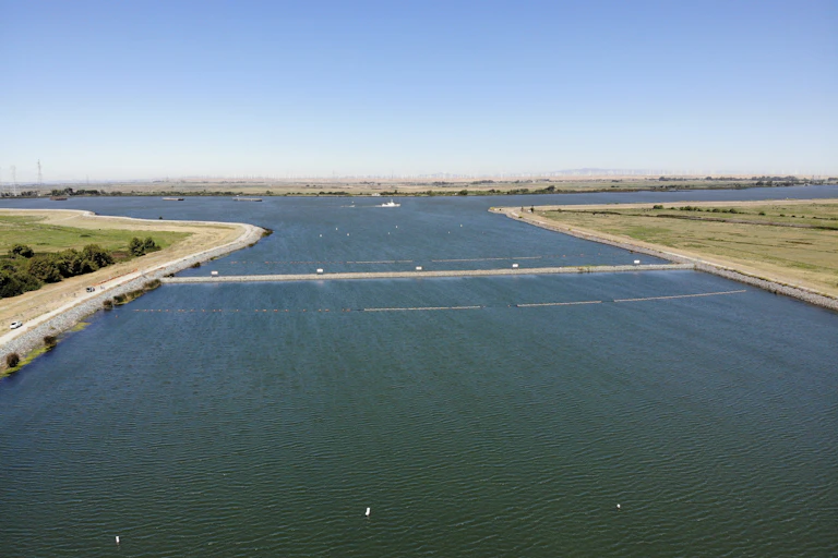 A barrier stretches across a wide water channel.