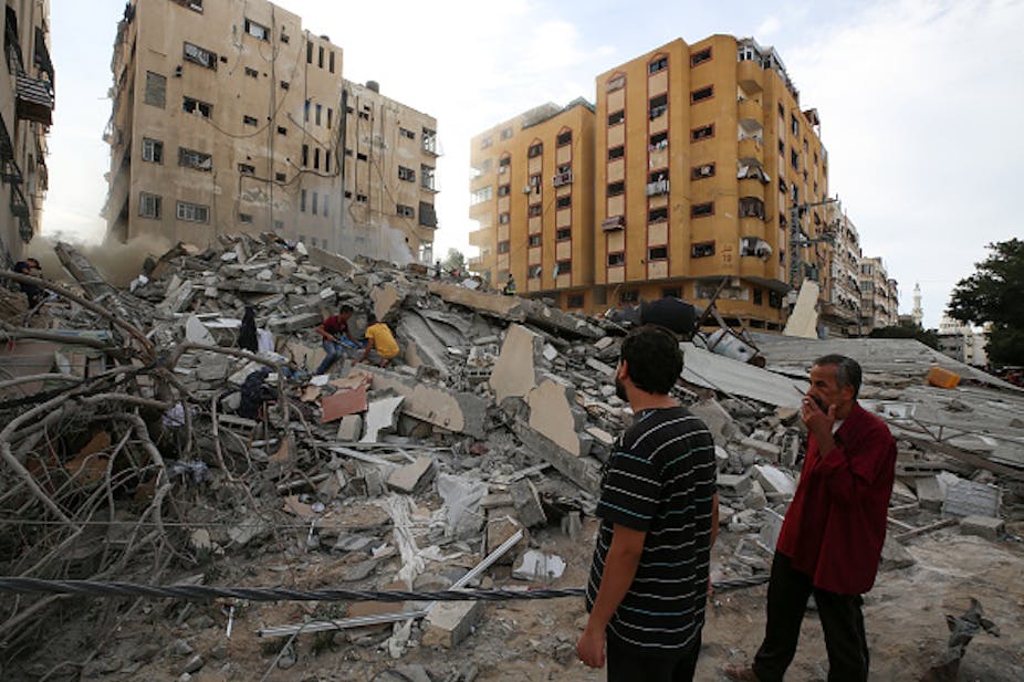 Two men assess the destruction cause by Israeli air strikes in Gaza City on October 7, 2023.