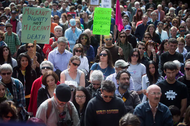People hold signs and bow their heads.