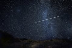 A bright shooting star with the Milky Way in the background