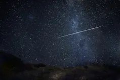 A bright shooting star with the Milky Way in the background