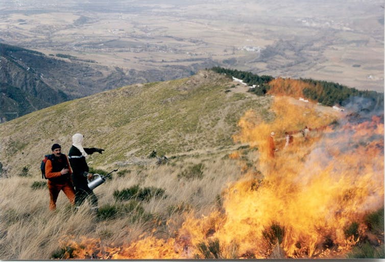 Dos personas junto a un fuego experimental.