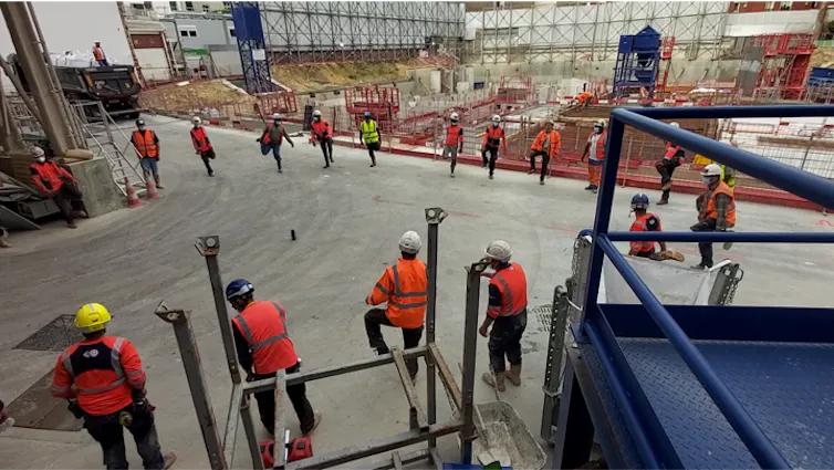 Des ouvriers font des exercices d’échauffement sur un chantier du BTP