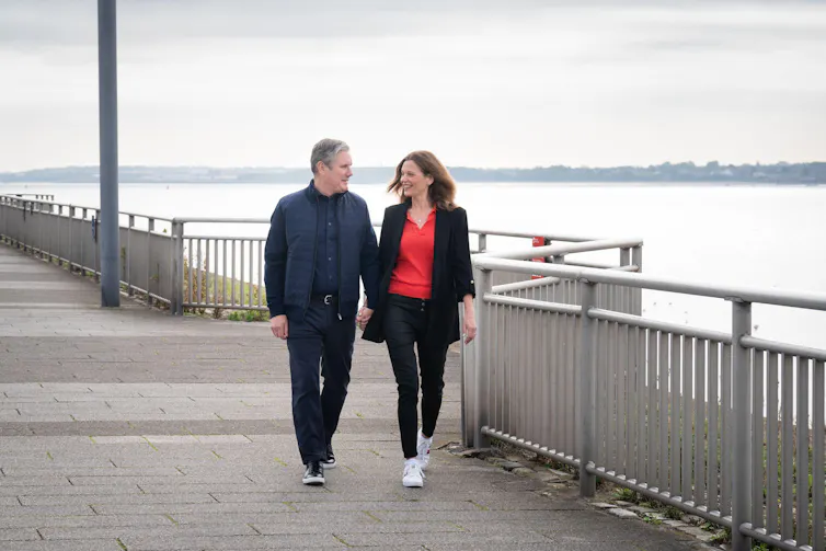 Keir Starmer walking with his wife alongside a large river.