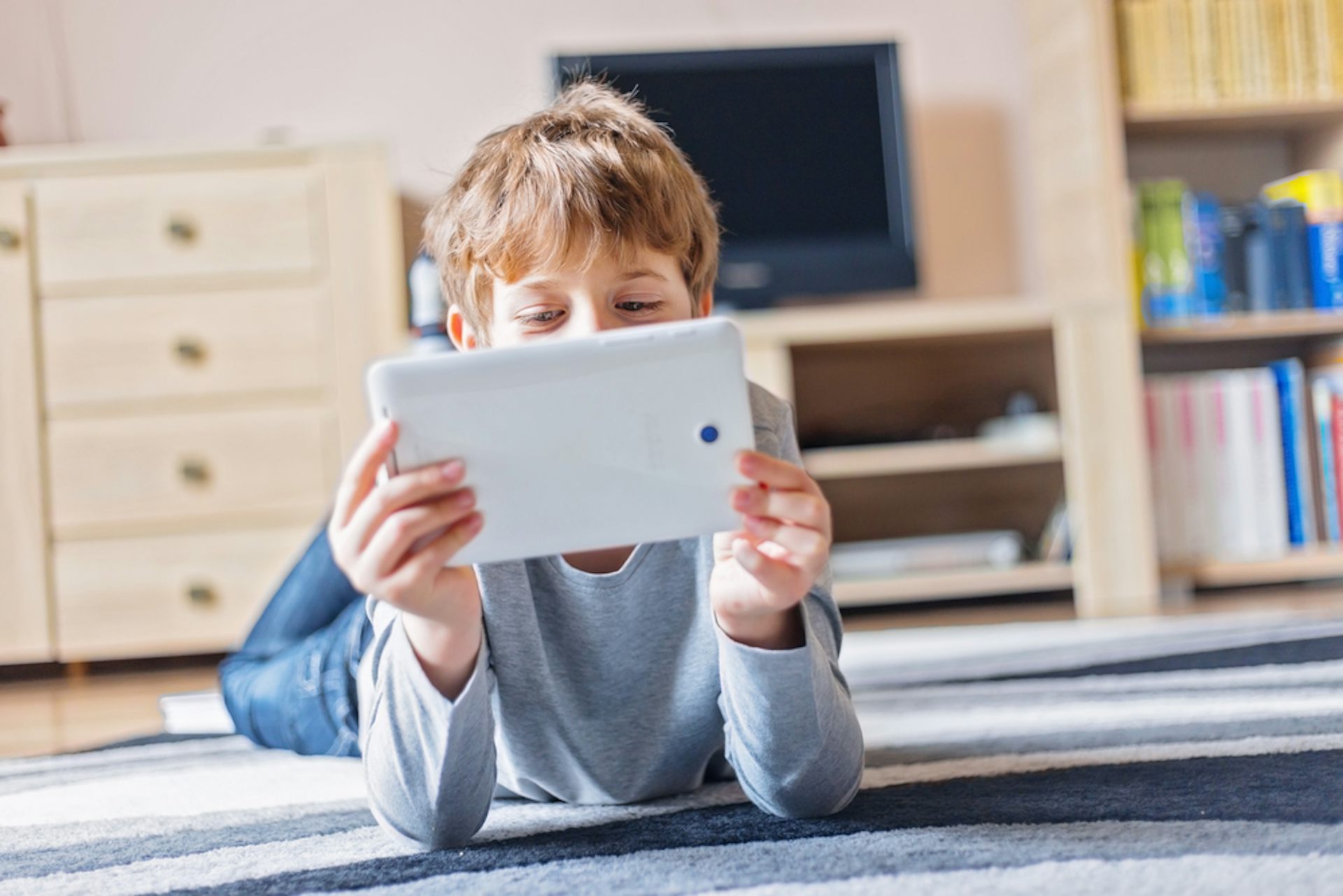 Enfant jouant avec une tablette dans un salon