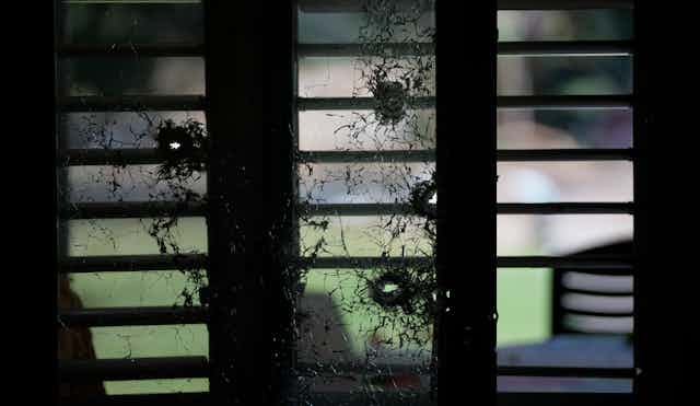 A bullet-riddled glass window.