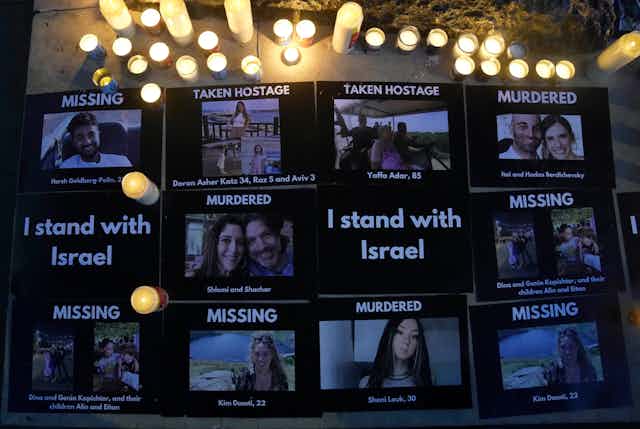 Signs on a board with photos of people and labels saying 'MISSING,' 'TAKEN HOSTAGE' or 'MURDERED.'