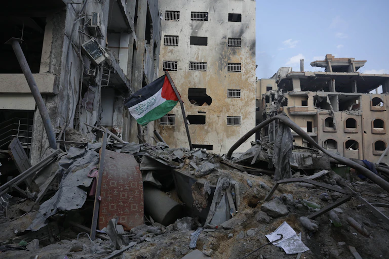 Bandeira da Palestina tremula em meio a escombros de um prédio destruído na Faixa de Gaza