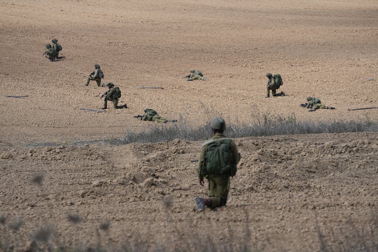 Soldiers kneel and lie on the ground.