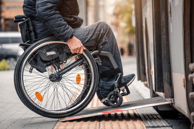 person in wheelchair boards bus via ramp