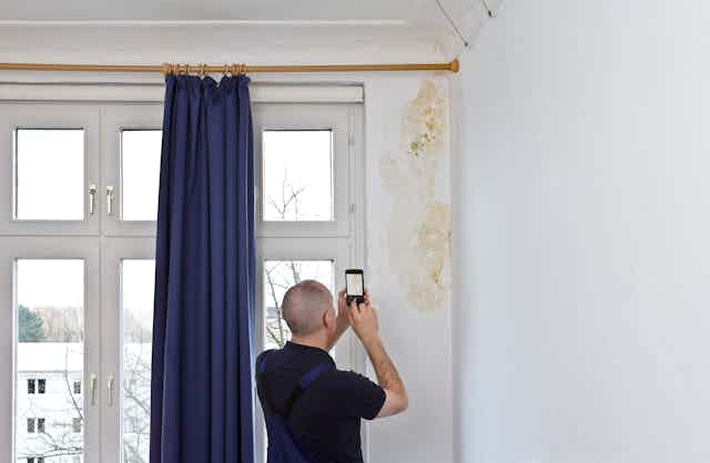 A man photographs mould in a house.