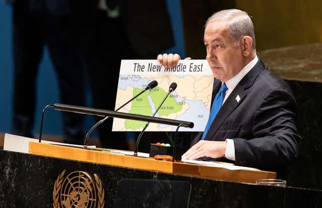 Israeli politician in suit holding map of 'New Middle East'.