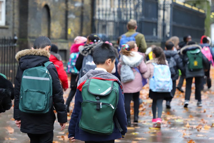 Children in school uniform with backpacks.