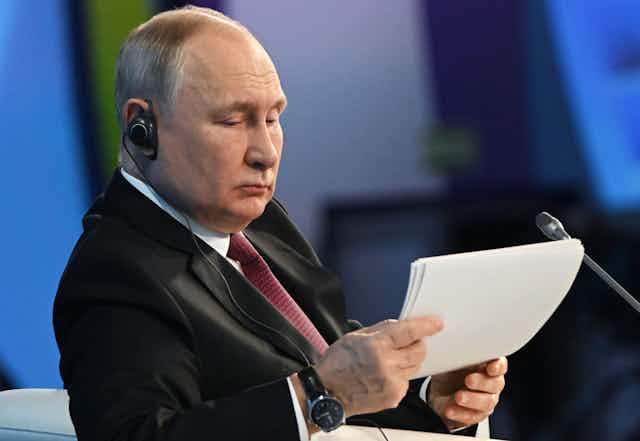 President Putin reading a paper in front of a microphone.