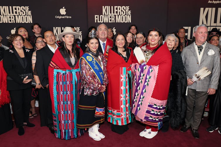 Tribal members, some in traditional garb, on a stage