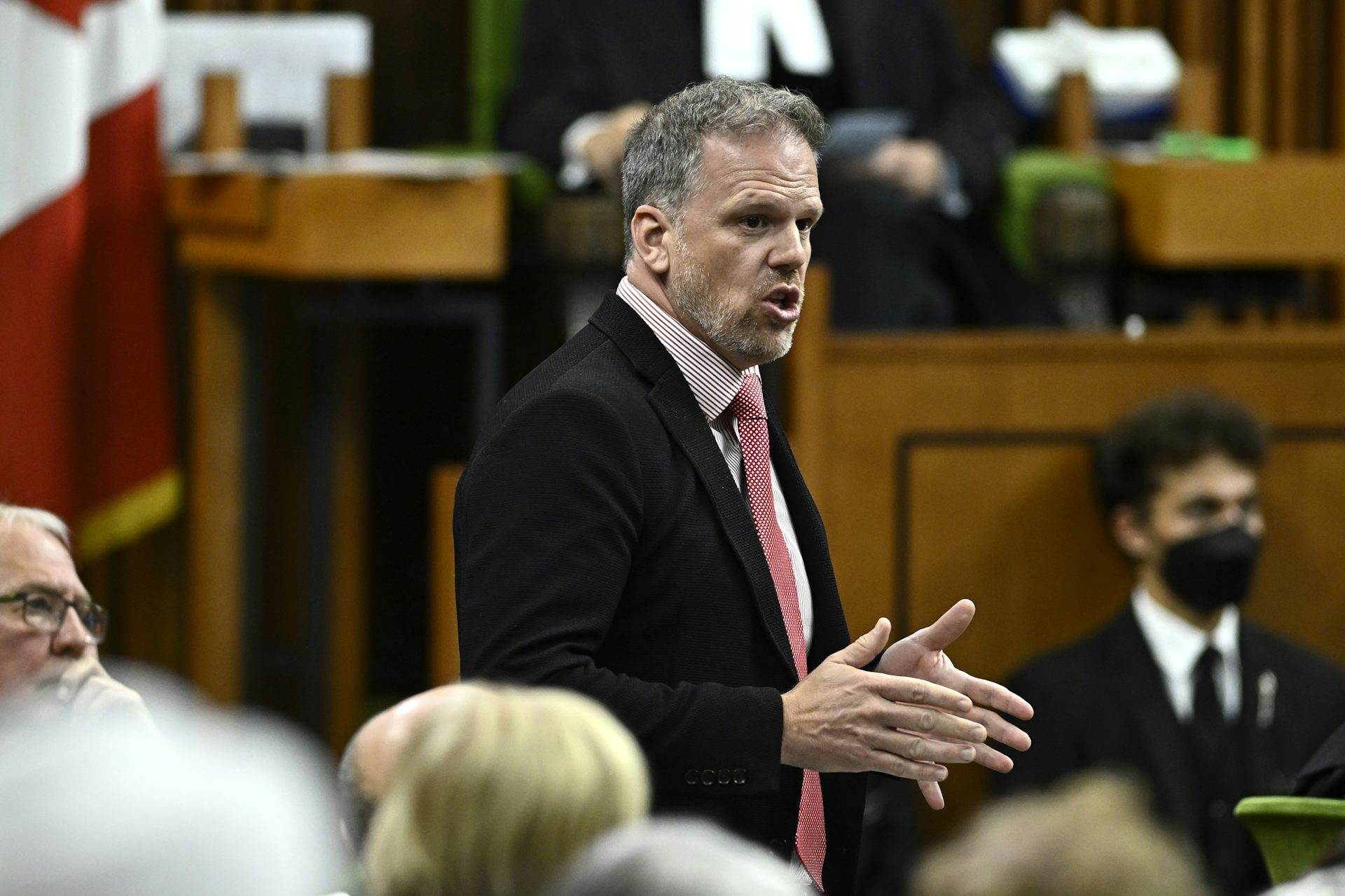 A man in a dark suit speaking